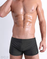 Front view of model wearing the SLIM GREEN men’s swimming bottoms in a solid dark green color by DC2, a men's beachwear brand from Miami.