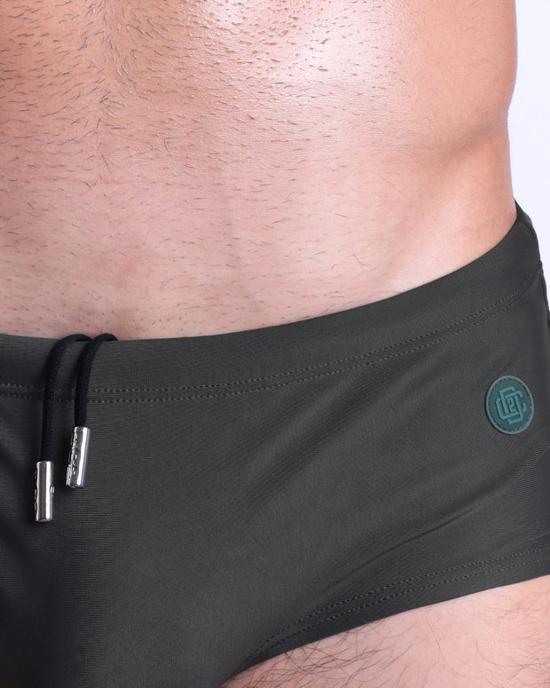 Close-up view of the SLIM GREEN men’s drawstring briefs showing black cord with custom branded metallic silver cord ends, and matching custom eyelet trims in silver.