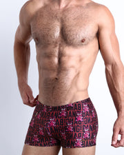 Side view of a masculine model wearing the STARSTRUCK compression swimwear shorts featuring black and red Tiger Pop Art Monogram graphic by BANG! Clothes.