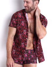 Frontal view of a male model wearing the STARSTRUCK Swim Trunks and the matching Stretch Shirt in a berry red color with hot pink tiger holding stars graphic by BANG! Clothes based in Miami, FL.