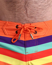 Close-up view of men’s summer beach shorts by BANG! clothing brand, showing orange cord with custom branded golden cord ends, and matching custom eyelet trims in gold.