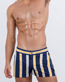 Frontal view of a masculine model wearing the SUN CHASING STRIPES beach shorts for men by DC2 Miami, a premium swimwear brand. 