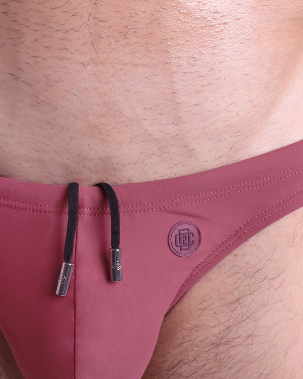 Close-up view of the SUNKISSED RED men’s drawstring briefs showing black cord with custom branded metallic silver cord ends, and matching custom eyelet trims in silver.