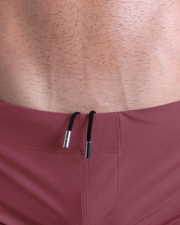 Close-up view of men’s summer beach shorts by DC2 clothing brand, showing black cord with custom branded metallic silver cord ends.