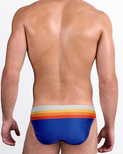 DC2 Sunset Stripes Swim Mini Brief — back view showing multicolor sunset stripe waistband and solid royal blue rear coverage.