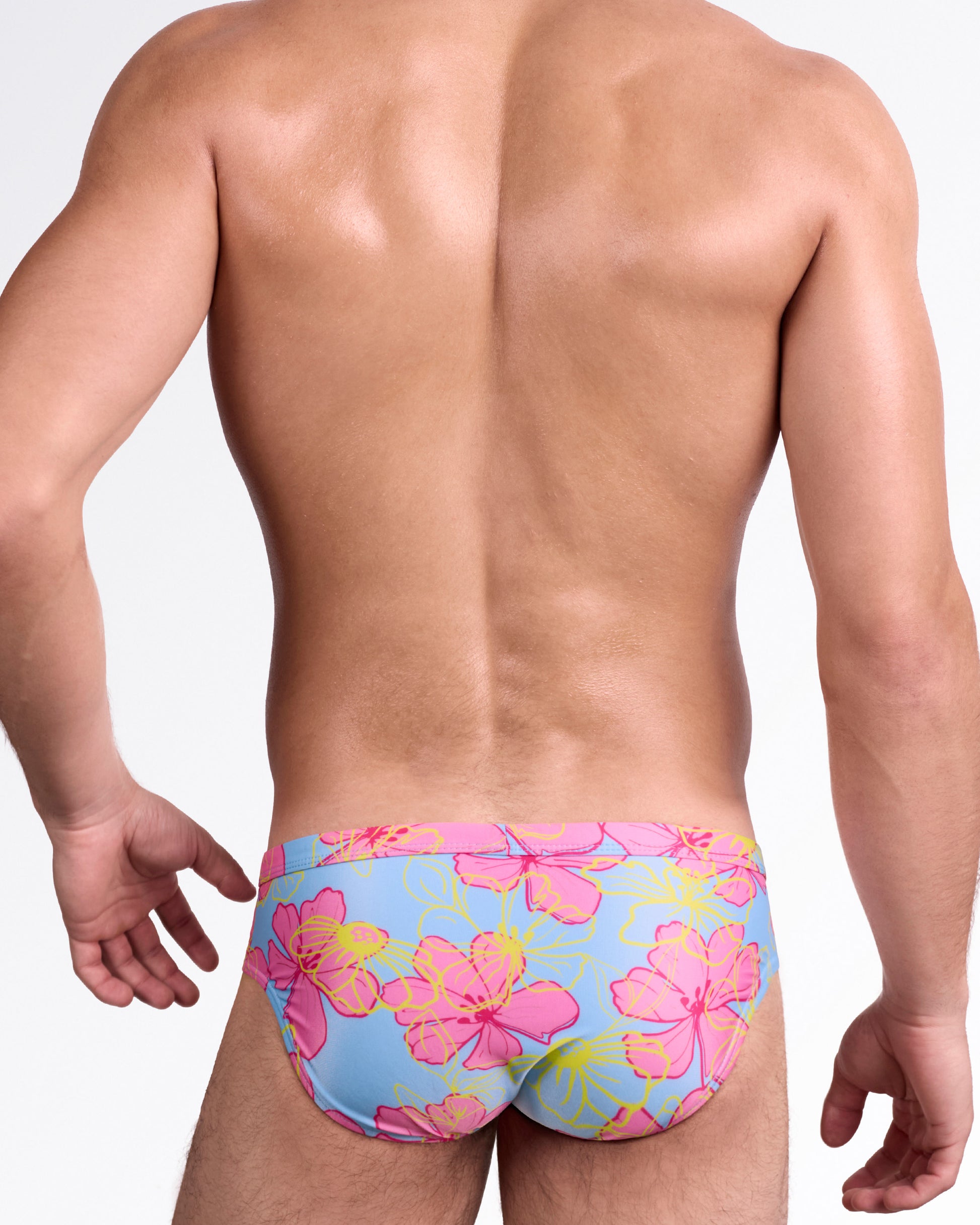 BANG Surf Flowers Pink Blue Swim Brief — back view highlighting full-coverage rear with bold tropical flower pattern in pink and yellow over blue background.