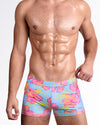 BANG Surf Flowers (Pink/Blue) — model wearing Flower Powers Swim Trunk featuring a sky blue base with oversized hibiscus-inspired florals in vibrant pink and neon yellow line detailing.