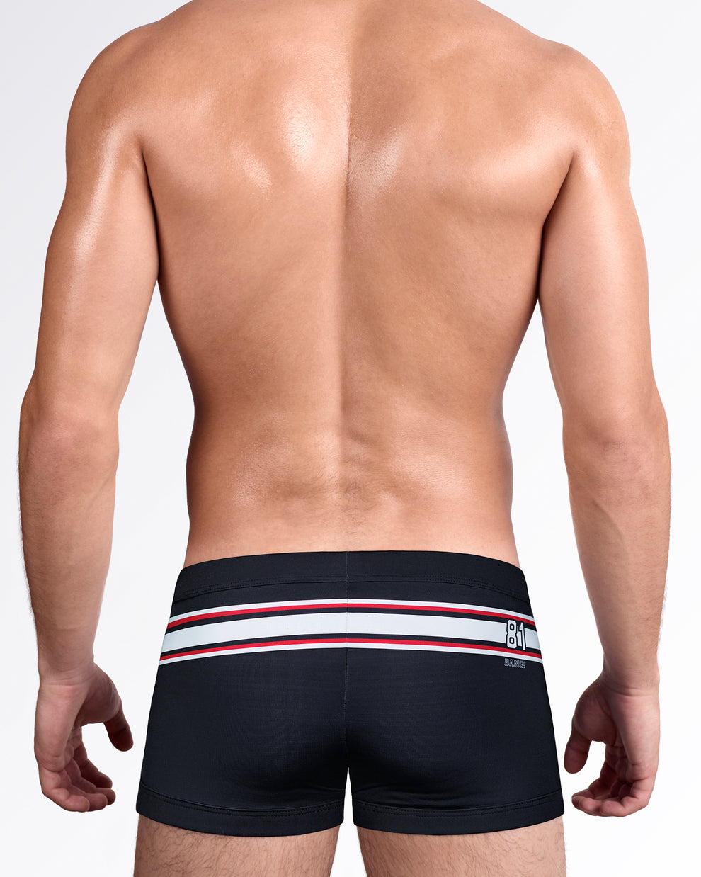 Back view of The Ilya Swim Trunks showcasing the streamlined square-cut fit, wraparound stripe detail, and premium men's swim trunks with back graphic accent.