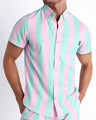 Male model wearing THE KEN (MALIBU EDITION) men’s sleeveless stretch shirt, with a stylish pastel pink and light aqua-colored stripes inspired by the styles seen worn by Ryan Gosling as Ken, in the Barbie movie. Designed by BANG! Clothes, a men’s beachwear brand from Miami.