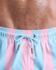 Close-up view of inseam and details of THE KEN (IBIZA EDITION) swimsuit for men, with light blue color cord and custom branded golden cord-ends, and matching custom eyelet trims in gold. 