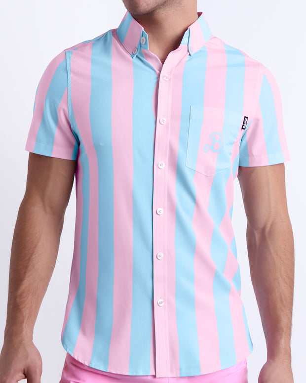 Male model wearing THE KEN (IBIZA EDITION) men’s sleeveless stretch shirt, in pink and light blue stripes inspired by the styles seen worn by Ryan Gosling as Ken, in the Barbie movie. Designed by BANG! Clothes, a men’s beachwear brand from Miami.