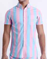 Male model wearing men’s THE KEN (IBIZA EDITION) men’s Summer button-down featuring pastel pink and blue colored stripes. This beach top is designed by BANG! Clothes in Miami.