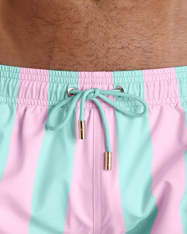 Close-up view of the THE KEN (MALIBU EDITION) men’s summer shorts, showing light seafoam green cord with custom branded golden cord ends, and matching custom eyelet trims in gold.