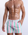 Male model wearing THE KEN (MALIBU EDITION) Tailored Shorts, premium swimwear in pink and light aqua-colored stripes inspired by the styles seen worn by Ryan Gosling as Ken, in the Barbie movie. Designed by BANG! Clothes, a men’s beachwear brand from Miami.