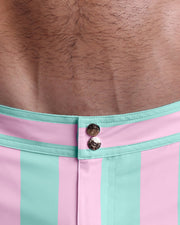 Close-up view of inseam and details of THE KEN (MALIBU EDITION) swimsuit for men, showing custom branded golden buttons.