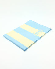 The Ken (Miami Edition) sand free microfiber beach towel. Featuring a chic striped design in pastel yellow and light sky blue colors with the BANG! logo in the corner, this soft, high-absorbency towel is perfect for stylish beach days.