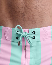 Close-up view of inseam and details of THE KEN (MALIBU EDITION) swimsuit for men, with aqua colored cord and custom branded golden cord-ends, and matching custom eyelet trims in gold.