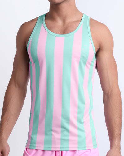 Male model wearing THE KEN (MALIBU EDITION) casual Tank Top, premium quality tank top in pink and light aqua-colored stripes inspired by the styles seen worn by Ryan Gosling as Ken, in the Barbie movie. Designed by BANG! Clothes, a men’s beachwear brand from Miami.