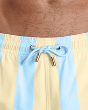 Close-up view of the THE KEN (MIAMI EDITION) men’s summer shorts, showing light blue cord with custom branded golden cord ends, and matching custom eyelet trims in gold.