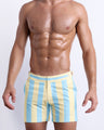 Male model wearing THE KEN (MIAMI EDITION) Tailored Shorts, premium swimwear in yellow and light blue-colored stripes inspired by the styles seen worn by Ryan Gosling as Ken, in the Barbie movie. Designed by BANG! Clothes, a men’s beachwear brand from Miami.