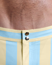 Close-up view of inseam and details of THE KEN (MIAMI EDITION) swimsuit for men, showing custom branded golden buttons.