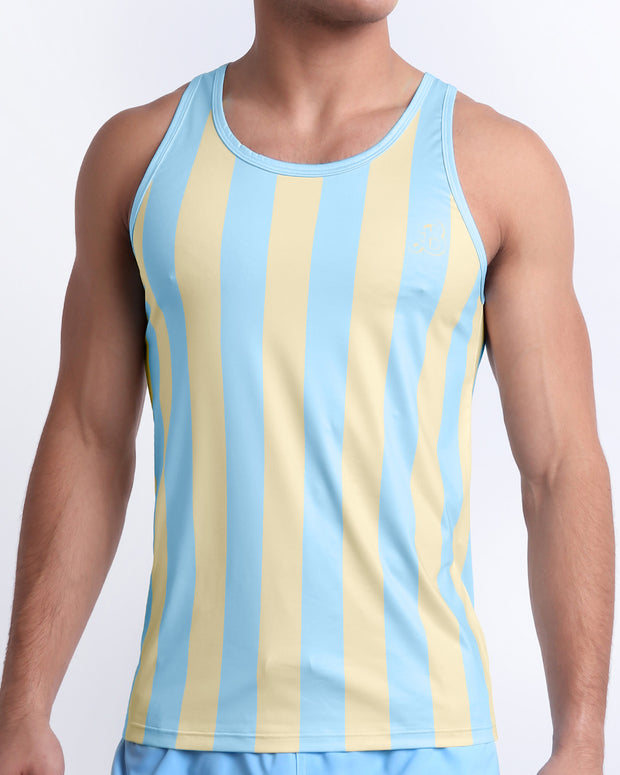 Male model wearing THE KEN (MIAMI EDITION) casual Tank Top, a premium quality tank top in yellow and light sky-colored stripes inspired by the styles seen worn by Ryan Gosling as Ken, in the Barbie movie. Designed by BANG! Clothes, a men’s beachwear brand from Miami.
