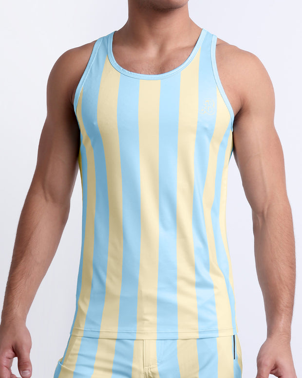 Male model wearing THE KEN (MIAMI EDITION) casual Tank Top, a premium quality tank top in yellow and light sky-colored stripes inspired by the styles seen worn by Ryan Gosling as Ken, in the Barbie movie. Designed by BANG! Clothes, a men’s beachwear brand from Miami.