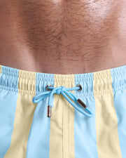 Close-up view of inseam and details of THE KEN (MIAMI EDITION) swimsuit for men, with light aqua green color cord and custom branded golden cord-ends, and matching custom eyelet trims in gold.