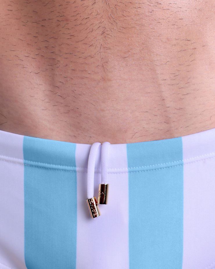 Close-up view of men’s summer Swim Sunga by BANG! clothing brand, showing white cord with custom branded golden cord ends, and matching custom eyelet trims in gold.