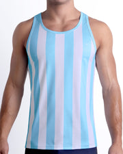 Male model wearing THE KEN (MYKONOS EDITION) casual Tank Top, in white and light blue-colored stripes inspired by the styles seen worn by Ryan Gosling as Ken, in the Barbie movie. Designed by BANG! Clothes, a men’s beachwear brand from Miami.