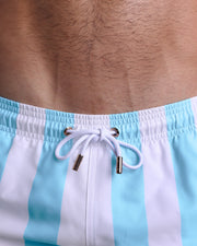 Close-up view of inseam and details of THE KEN (MYKONOS EDITION) swimsuit for men with custom branded golden cord-ends, and matching custom eyelet trims in gold. 