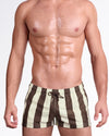 BANG The Ken (Sahara Edition) Show Shorts — model wearing desert-inspired striped show shorts featuring alternating sand and espresso brown vertical stripes with a tailored short-length silhouette and adjustable drawstring waistband.
