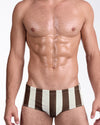 BANG The Ken (Sahara Edition) Swim Sunga — model wearing warm brown and sand vertical stripe design, featuring a tailored low-rise sunga silhouette with clean waistband finish and structured front pouch.
