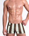 BANG The Ken Sahara Edition Swim Trunks — model wearing fitted men’s swim trunks featuring wide vertical brown and sand beige stripes with a tailored athletic fit.