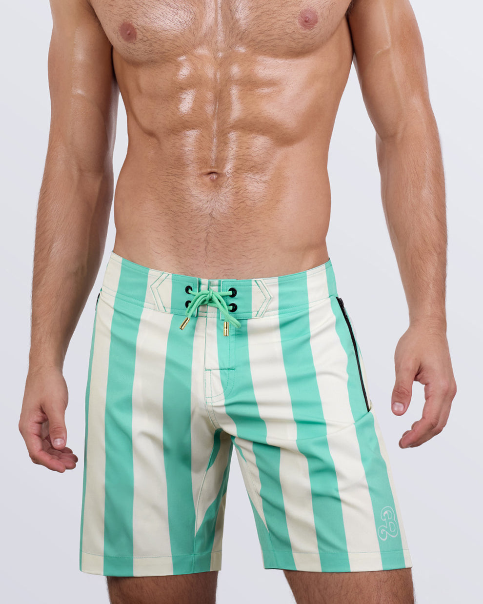 Close-up side view of a male model in the THE KEN (TULUM EDITION) - Flex Boardshorts by BANG! Miami. The design includes deep zippered pockets for secure storage, premium metal-tipped drawstrings, and a streamlined silhouette for a sleek, athletic look.