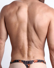 Back view of a Male model wearing beach swim bikini Swimsuit for men featuring a black and brown Tiger Pop Art Monogram print by the Bang! Clothes brand of men's beachwear.