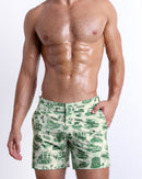 Male model wearing the TOILE DE MIAMI (GREEN) Tailored Shorts, premium swimwear in beige and dark green-colored toile de jouy inspired print. Designed by BANG! Clothes, a men’s beachwear brand from Miami.