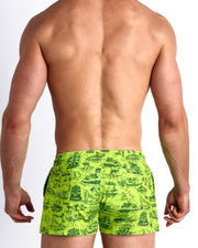Back view of male model wearing the TOILE DE MIAMI (NEONE GREEN/BLUE) beach trunks in lime green with blue Miami inspired artwork for men by BANG! Miami.