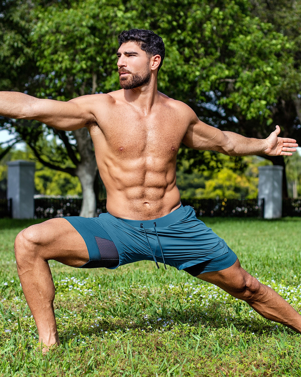 DC2 Miami Teal Endurance 2-in-1 Gym Shorts — model wearing teal men’s training shorts in an outdoor yoga pose.