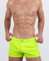 DC2 Ultra Neon Mini Shorts — model wearing bright neon men's swim shorts with button waist and short leg cut.