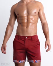 Front view of a male model wearing UNDER MY UMBRELLA men's chino shorts in a solid red color with reversible cuff that reveals DC2® signature print when flipped out. Designed by DC2 a BANG! Miami Clothes capsule brand.