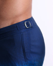 Close-up view of the UNDER MY UMBRELLA men’s swimwear, showing custom-branded silver adjustable side buckles.