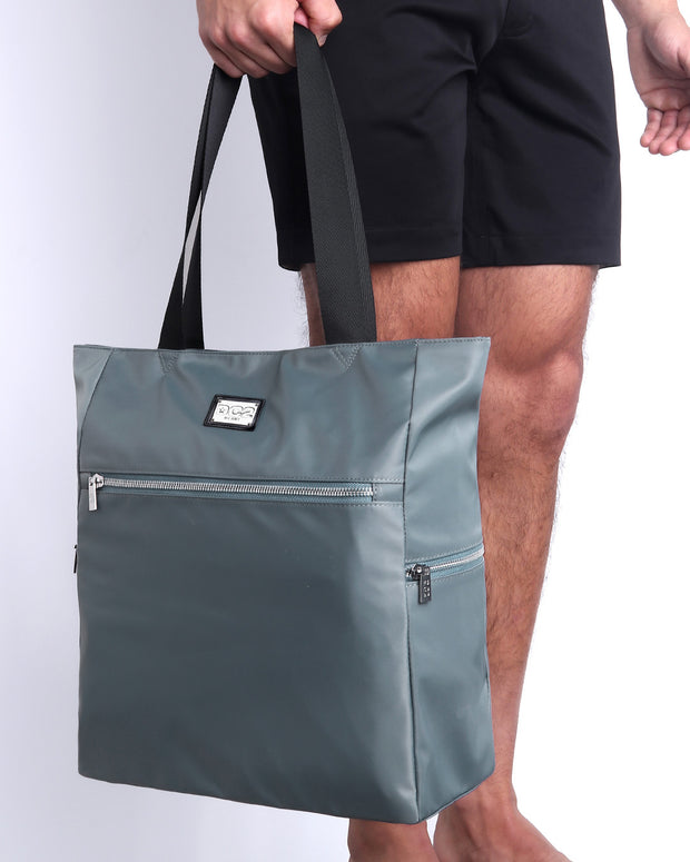 Side view of the VACAY GRAY Poolside Tote Bag Foldable/Portable by DC2 brand. Features smooth zipper in the front and the side, water resistant fabric, and the DC2 logo in a metallic silver plaque.