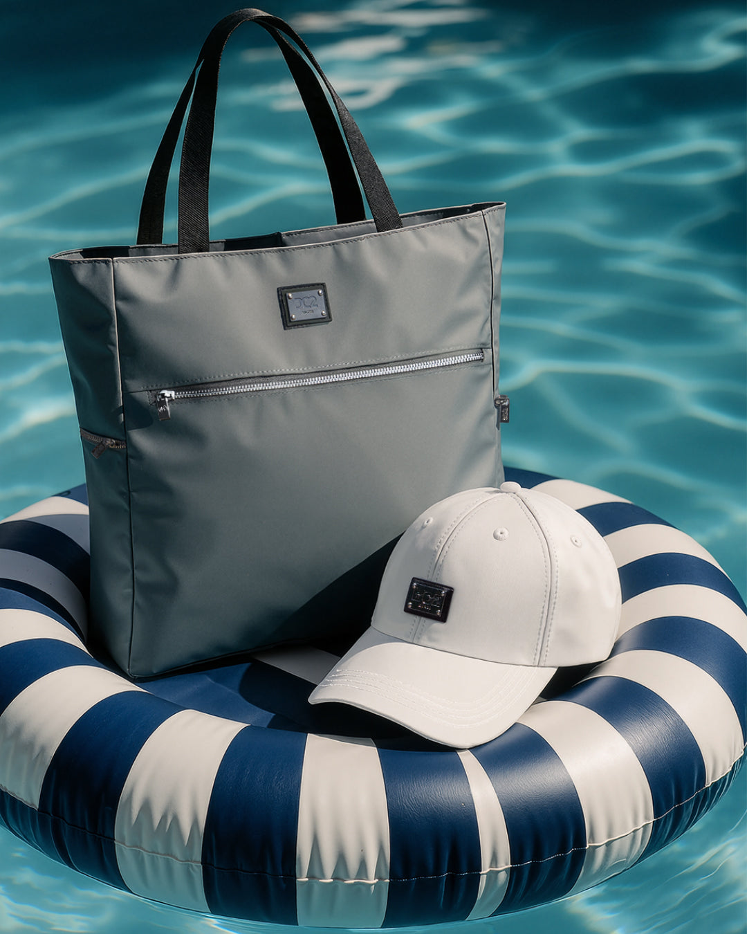 DC2 Vacay Gray Poolside Tote and White Chillax Cap — sleek summer essentials featuring a waterproof tote with zip pocket and lightweight structured cap with logo.