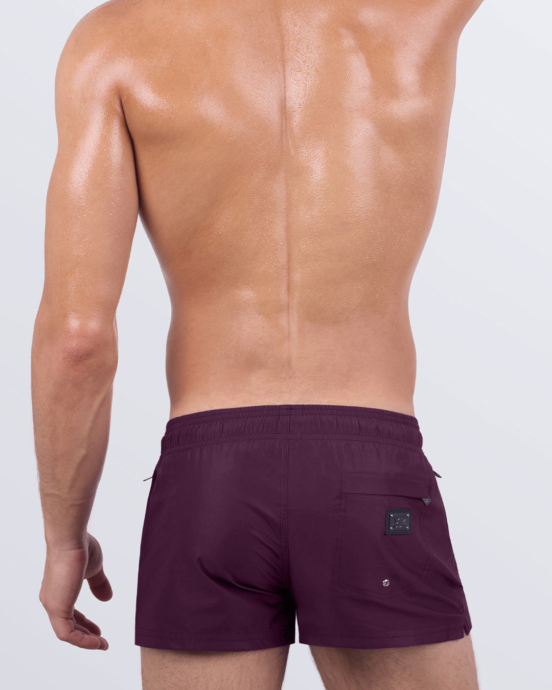 Back view of VERY BERRY men’s poolside shorts showcasing contoured fit, elastic waistband, and rear pocket with metallic logo detail in deep berry tone.