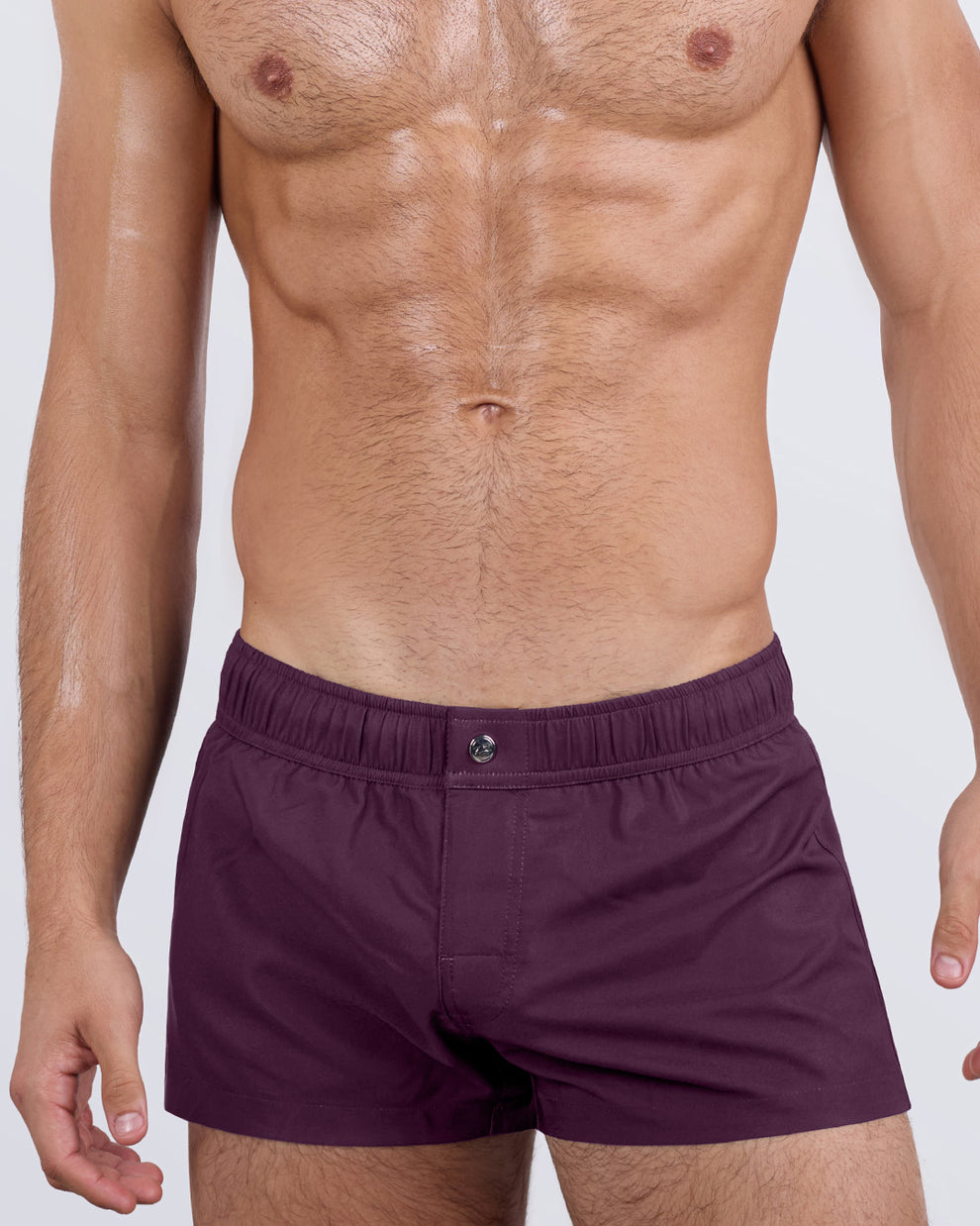 Close-up side view of a male model wearing the VERY BERRY Mini Shorts for men by DC2 Miami. These ultra-short swim shorts feature a hidden internal mini-pocket, four-way stretch fabric for flexibility, and a contoured fit that enhances the legs and waist.