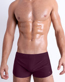 Front view of model wearing the BERRY GOOD men’s swimming bottoms in a solid dark berry color by DC2, a men's beachwear brand from Miami.