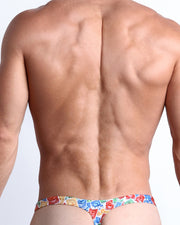 Back view of a Male model wearing the VIA POSTAL beach swim bikini Swimsuit for men in a colorful postal stamps graphic by the Bang! Clothes brand of men's beachwear.