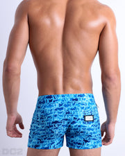 Back view of a male model wearing men’s Summer WET Beach Shorts featuring a monogram print of the DC2 logo print, complete with a back zippered pocket, designed by DC2.