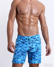 Male model wearing the WET Flex Boardshorts, premium swimwear with a stylish DC2 logo monogram motif in blue for men. These high-quality swimwear bottoms by DC2, a men’s beachwear brand from Miami.